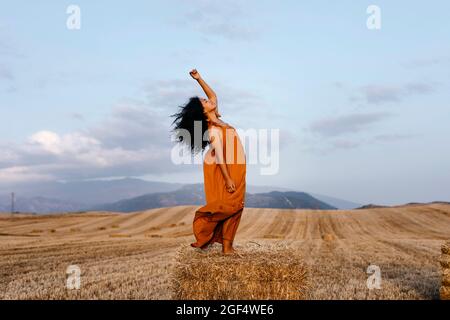 Woman dancing while standing at meadow Stock Photo
