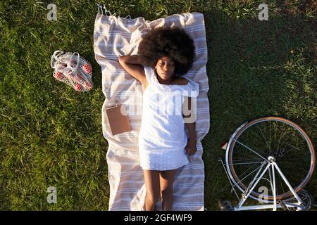 Afro woman sleeping on picnic blanket at park Stock Photo