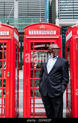 Businessman with hands in pockets standing near telephone booth Stock Photo