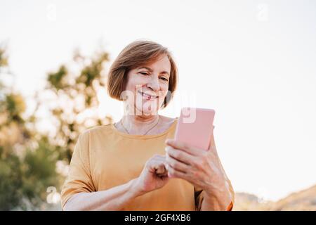 Smiling senior woman using smart phone Stock Photo