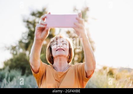 Senior woman photographing through through smart phone Stock Photo