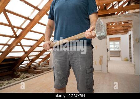 Construction worker with a hammer during the renovation of the attic of a house. Stock Photo
