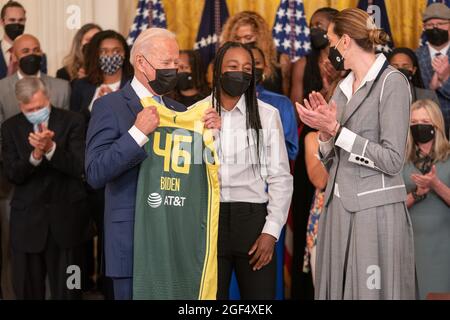 Washington, United States. 23rd Aug, 2021. President Joe Biden is given a team jersey Jewell Loyd, center and Breanna Stewart, right, of the Seattle Storm after they won the 2020 WNBA Championship at the White House in Washington, DC on Monday, August 23, 2021. Photo by Ken Cedeno/Pool/Sipa USA Credit: Sipa USA/Alamy Live News Stock Photo