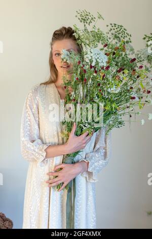 Young woman holding bouquet of wild flowers in studio Stock Photo