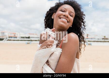 Smiling woman with eyes closed wearing beach towel on sunny day Stock Photo