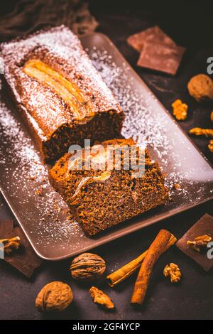 Homemade vegan banana bread or cake with nuts, chocolate and cinnamon on brown background Stock Photo