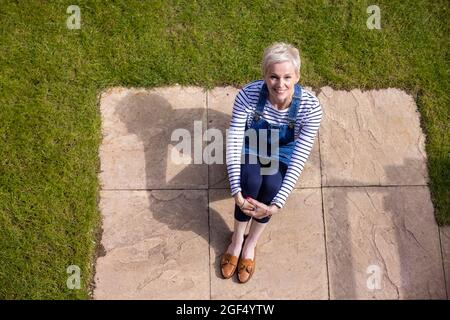 Smiling woman hugging knees while sitting at garden Stock Photo