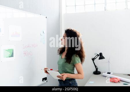 Businesswoman with digital tablet analyzing charts while working at office Stock Photo