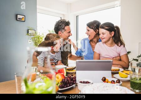 Happy man and woman looking at each other with kids at home Stock Photo