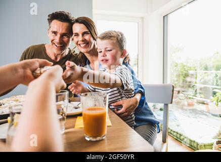 Brother passing pie to sister while having breakfast at home Stock Photo
