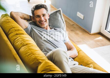 Smiling man relaxing on sofa at home Stock Photo