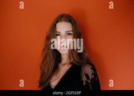 Beautiful young woman with long brown hair against red background Stock Photo