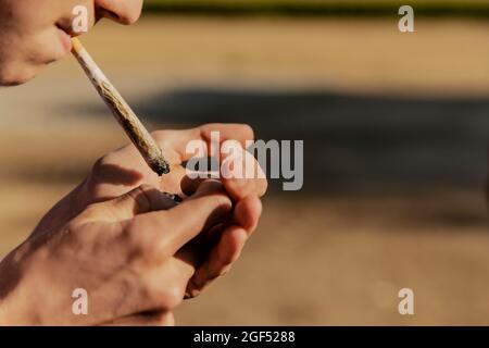 Teenage boy igniting marijuana joint during sunset Stock Photo