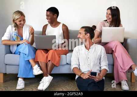 Cheerful male and female coworkers using laptops and mobile phone at office Stock Photo