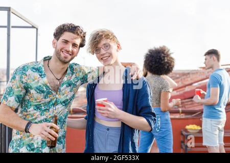 Smiling young friends having drinks on penthouse terrace Stock Photo