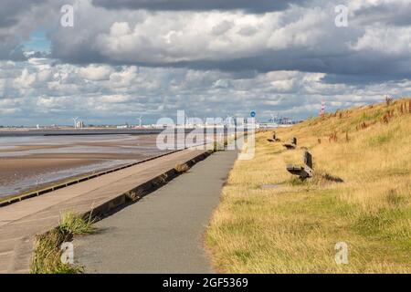 Wallasey, UK: Cycle path and embankment along the North Wirral Coastal Park, looking towards Liverpool docks in the distance. Stock Photo