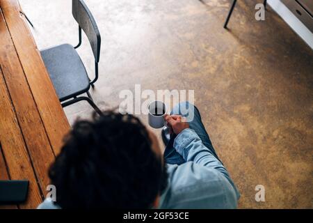 Man holding coffee cup while sitting at table Stock Photo