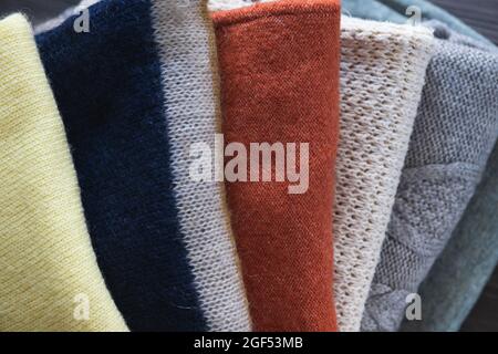 Knitted woolen clothes on wooden table close-up. Autumn or winter background. Stock Photo