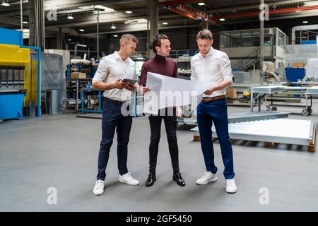 Business professionals analyzing blueprint at factory Stock Photo