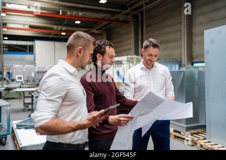 Male engineers checking blueprint at industry Stock Photo