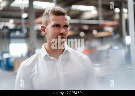 Thoughtful young businessman looking away in industry Stock Photo