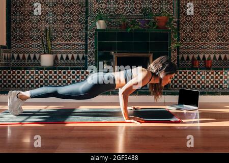 Young fit woman practicing plank while working out at home Stock Photo