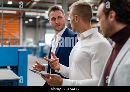 Male professionals discussing while working at industry Stock Photo