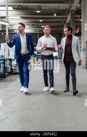 Male professionals discussing while walking at industry Stock Photo