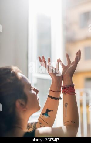 Woman with hands raised meditating at home Stock Photo