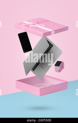 Laptop  computer, smart phone and smart watch in open  gift box while levitating in the air. Creative minimal concept of gifts and delivery. Suitable Stock Photo