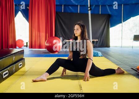 Female acrobat stretching legs while doing rehearsal in circus Stock Photo