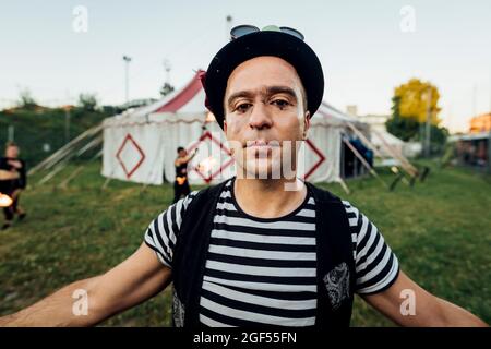 Male acrobat with arms outstretched standing outside circus tent Stock Photo
