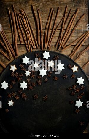 Cinnamon sticks, star anise, and Christmas cookies lying on rustic baking sheet Stock Photo