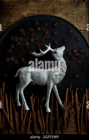 Cinnamon sticks, star anise and silver colored deer figurine lying on rustic baking sheet Stock Photo