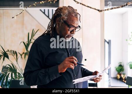 Senior male professional checking documents at home Stock Photo