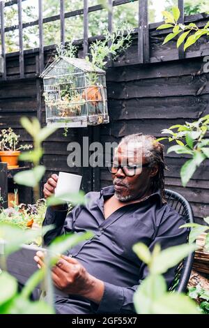 Senior businessman using digital tablet while holding mug in backyard Stock Photo