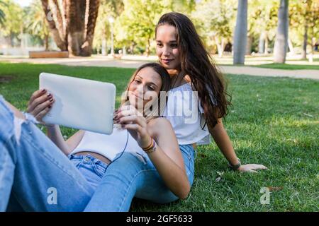 Young female friends using digital tablet at public park Stock Photo