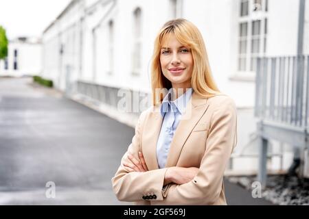 Confident female professional with arms crossed wearing beige blazer Stock Photo