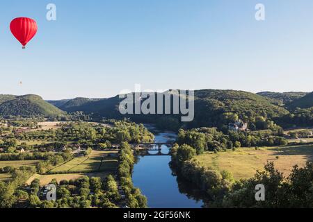 Red hot air balloon flying against clear sky over Dordogne River Stock Photo