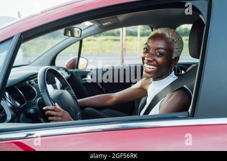 Cheerful young woman sitting in car Stock Photo