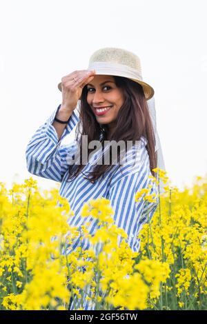 Smiling woman wearing hat in yellow field Stock Photo