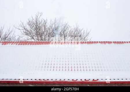 The roof made of metal tiles is covered with falling snow. Reliable roof in winter. Stock Photo