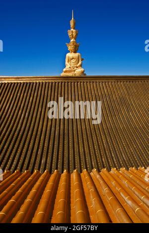 China, Sichuan, Emeishan City, Tiled roof of Buddhist temple at summit of Mount Emei with golden statue of Samantabhadra in background Stock Photo