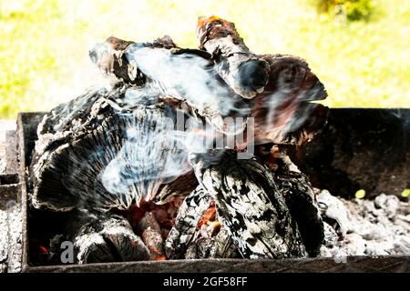 Campfire coals, Firewood burning on grill. Texture fire bonfire embers. Smoldering fire. The hot embers of burning wood log fire. Stock Photo