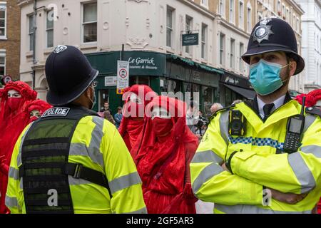 London, UK. 23rd Aug, 2021. Members of the Extinction Rebellion Red Rebel Brigade seen facing off with Police officers during the Extinction Rebellion's day one of a two week demonstration in Central London.Extinction Rebellion held a protest against climate change, global warming, which plans to target the root cause of the climate and ecological crisis and to demand the government divest from fossil fuel companies ahead of COP26 the 2021 United Nations Climate Change Conference. (Photo by Dave Rushen/SOPA Images/Sipa USA) Credit: Sipa USA/Alamy Live News Stock Photo