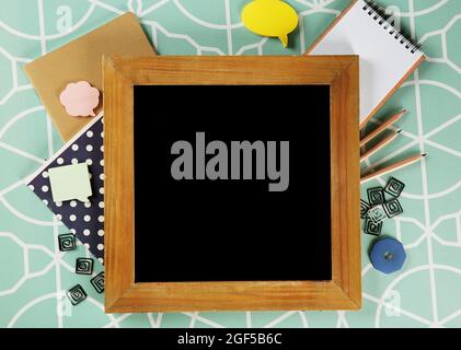 Small school blackboard with stationery on patterned background
