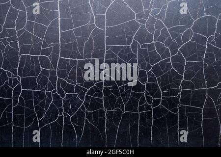 Many chaotic cracks on the surface of the black textured material. Stock Photo