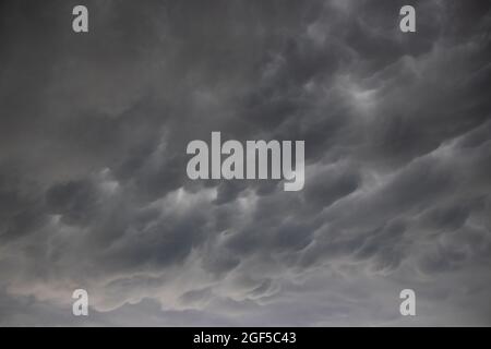 A wide angle cloudscape shot of dramatic clouds in a dark and stormy sky, a thunderstorm with backlit grey clouds, ominous and spooky Stock Photo