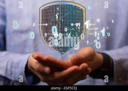 Man holding a 3D shield icon symbolizing data security and protection Stock Photo