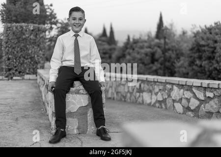 Grayscale shot of an adorable male child in a formal suit outfit posing Stock Photo